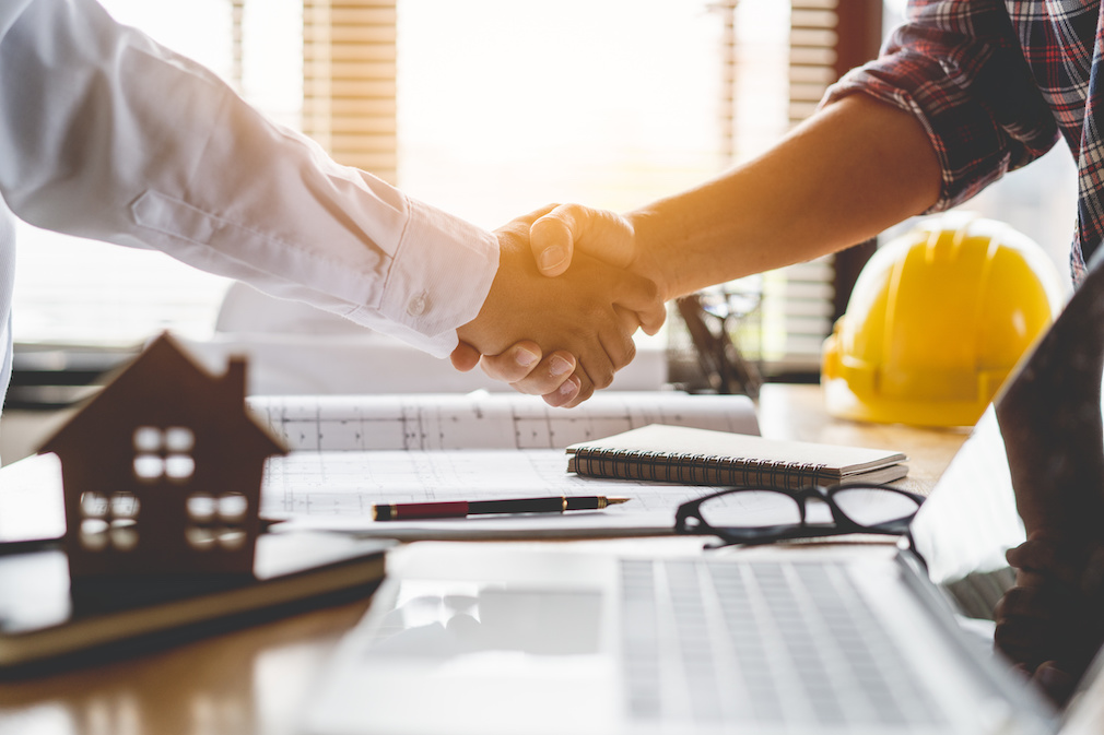 Client shaking hands with contractor after confirm blueprint to renovate house.
