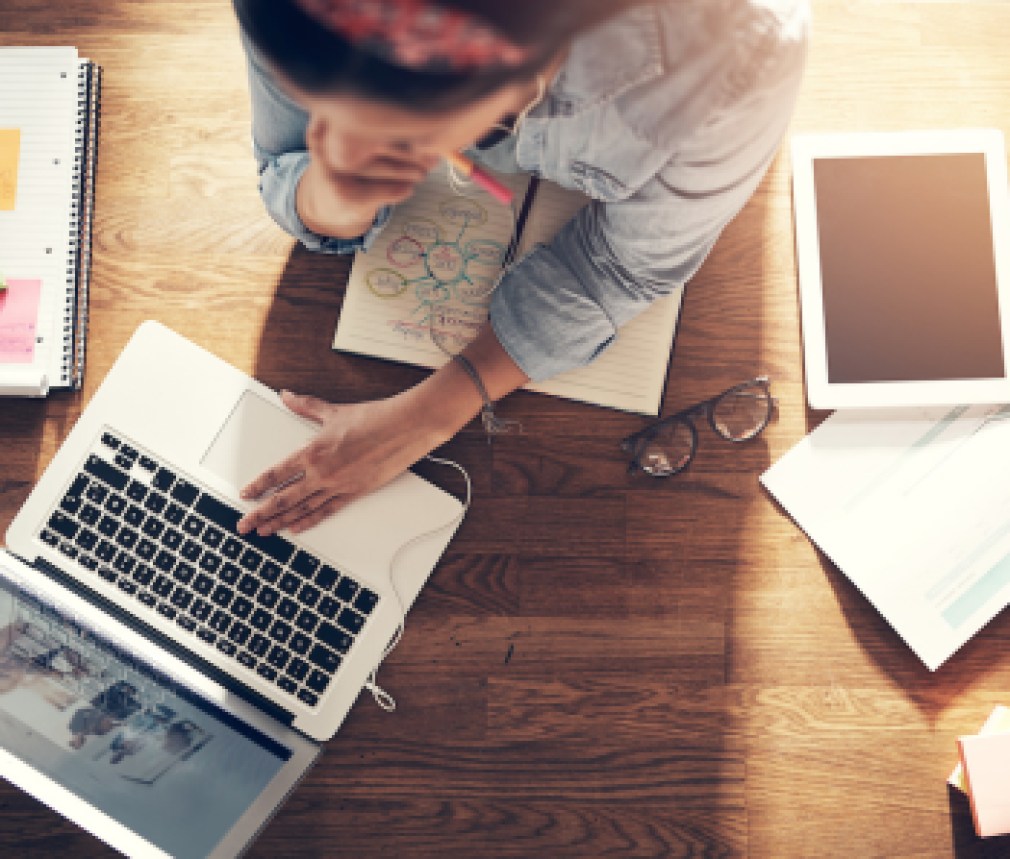 Young female entrepreneur thinking and browsing laptop in office