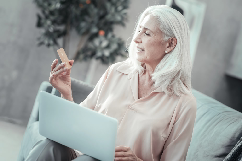 Positive senior woman looking at her credit card