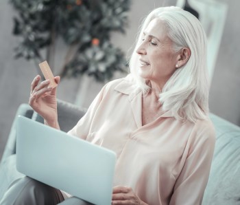 Positive senior woman looking at her credit card