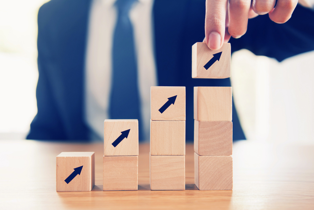 Business concept growth success process, Close up Businessman hand arranging wood cube with arrow stacking as step stair.