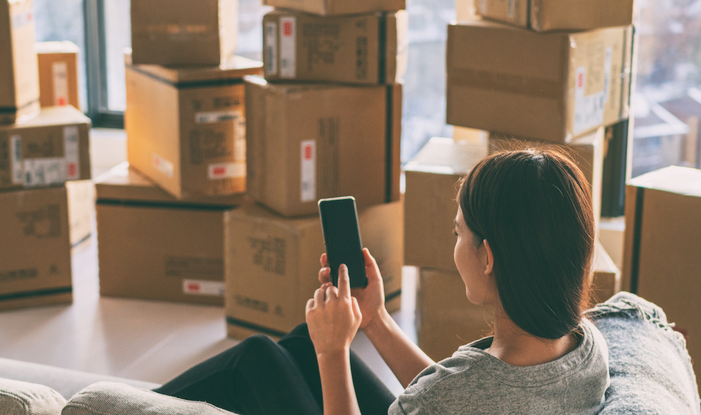 Moving boxes woman using phone panoramic for move to college leaving apartment ready for movers pick-up with packages of cardboard box for new home move in. Banner.