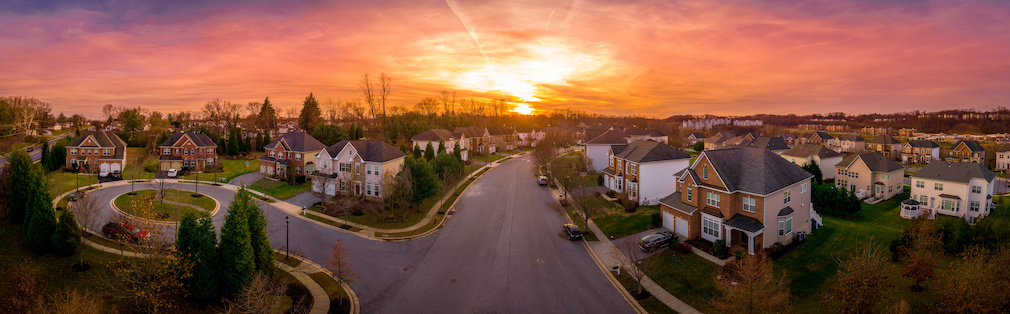 Aerial sunset panorama view of luxury upscale residential neighborhood gated community street in Maryland USA, American real estate with single family homes brick facade cul-de-sac (dead-end)