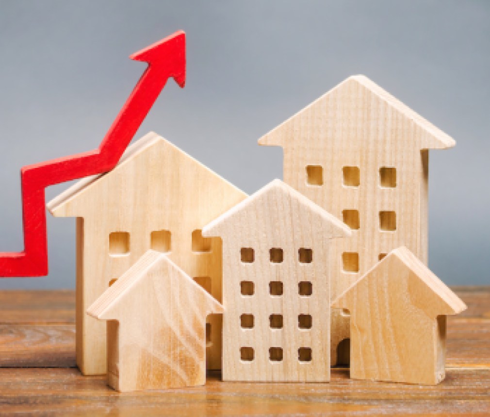 Miniature wooden houses and red arrow up. The concept of increasing the cost of housing. High demand for real estate. The growth of rent and mortgage rates. Sale of apartments. Population grows