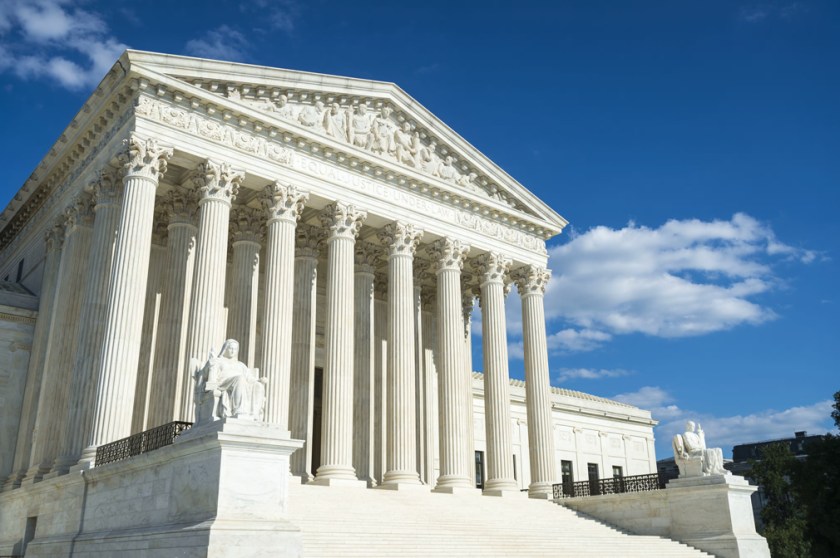 Supreme Court of the United States building front entrance with a scenic view of columns and steps under bright summer sun in Washington DC, USA