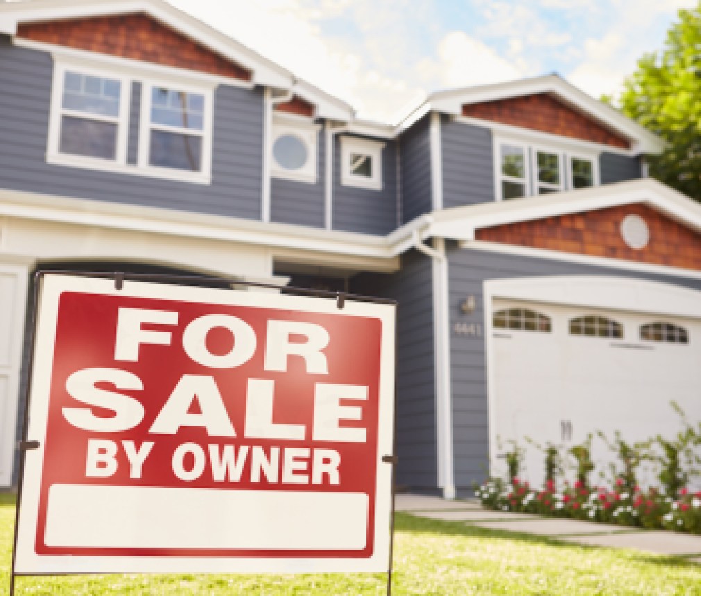 Large suburban house with ‘for sale’ sign displayed outside