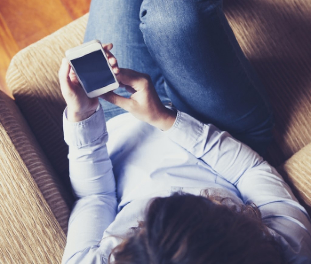 Aerial view of girl reading a phone while sitting in a couch. Vintage tone.