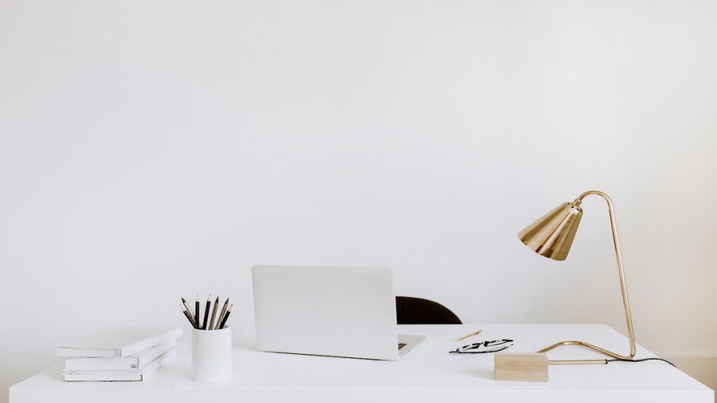 Office with laptop, lamp, notebooks. White working study cabinet. Outsourcing freelancer, blogger, boss workspace.