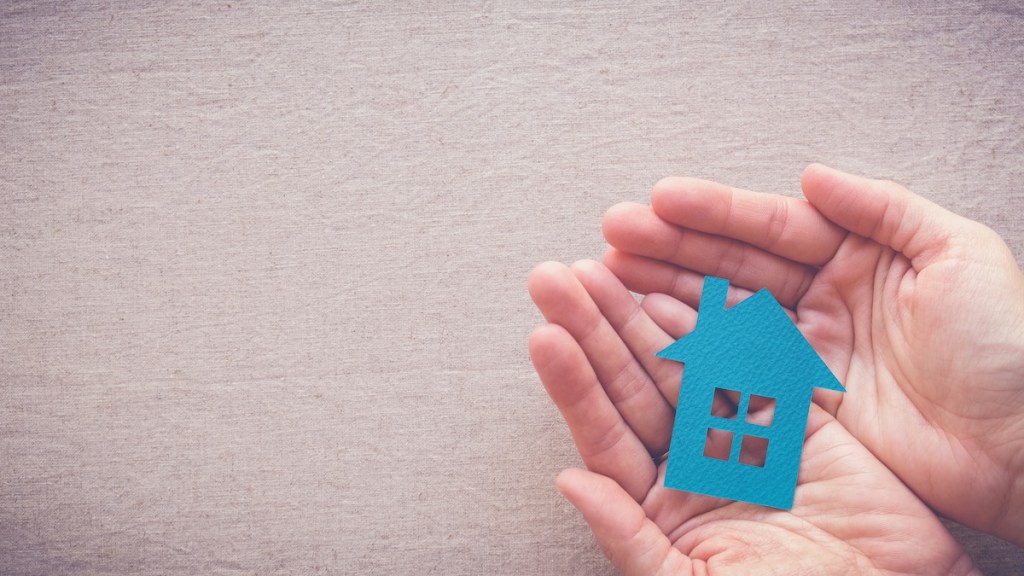 hands holding paper house, homeless shelter and real estate concept
