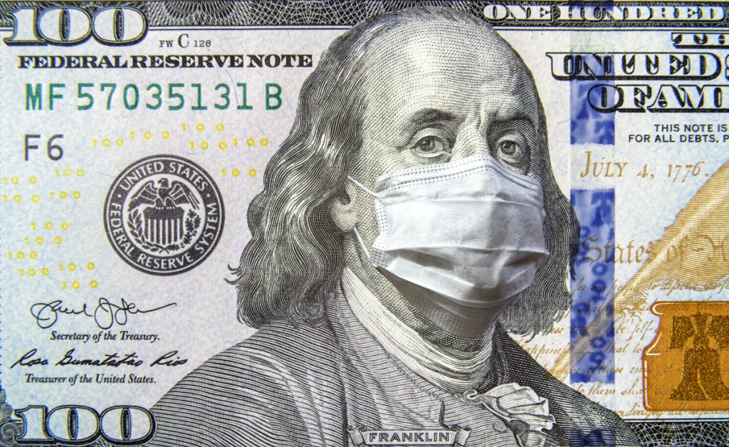 COVID-19 coronavirus in USA, 100 dollar money bill with face mask. Coronavirus affects global stock market.