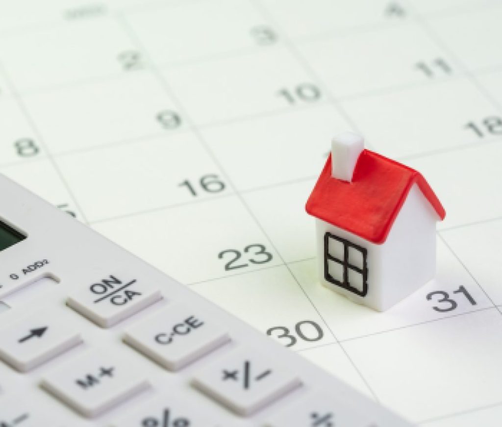 House mortgage payment and installment schedule concept, small miniature house on end of month calendar with calculator
