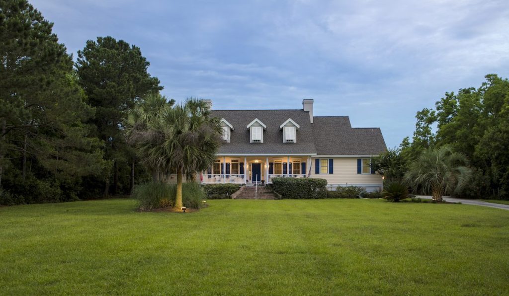 Beautiful cape cod home at twilight with large lawn.