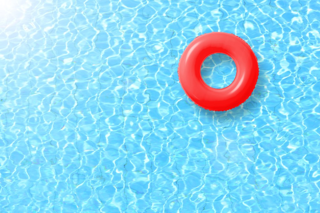 red swimming pool ring float in blue water and sun bright. concept color summer.