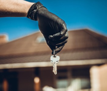 Keys in hand in black glove. Use alcohol spray to corona virus and kill germs at the key of the house or office regularly. Covid-19 ncov or coronavirus quarantine concept.