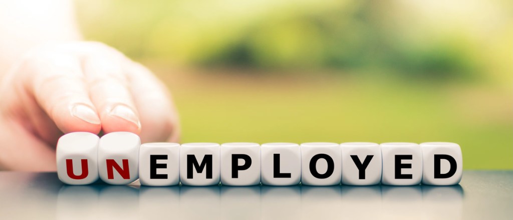Hand turns dice and changes the word "unemployed" to "employed".