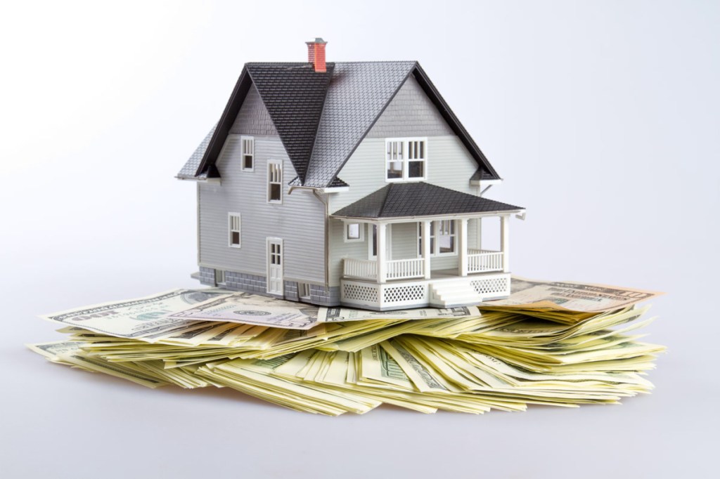 Model of a House on Money on Grey Background