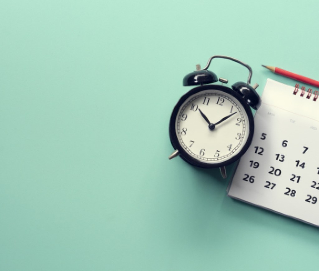 close up of calendar and alarm clock on the green background, planning for business meeting or travel planning concept