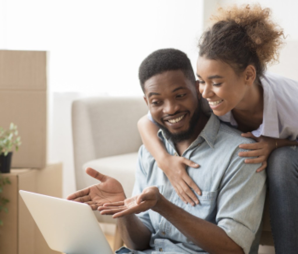 Husband Using Laptop Showing Something Wife Sitting On Couch Indoor