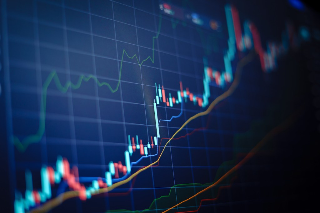 Closeup financial chart with uptrend line candlestick graph in stock market on blue color monitor background