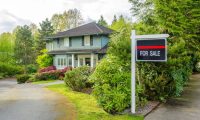 real estate for sale sign in front of a green house