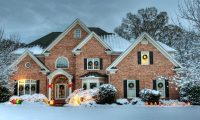 large brick two story home in the snow with christmas decorations