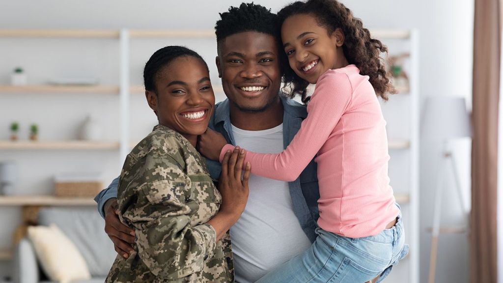 Military family including a mom in uniform, her husband and daughter in dad's arms