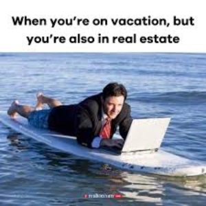 Man in suit and tie on a surfboard in the ocean with laptop