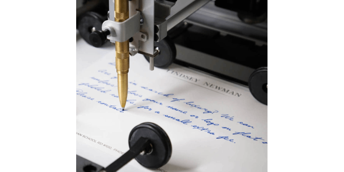 Robotic machine holding blue ballpoint pen to write handwritten postcards.